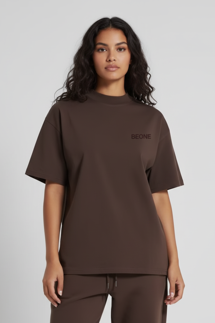 Woman wearing a brown t-shirt with 'BEONE' branding on a light gray background