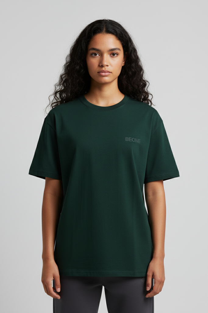Person wearing a dark green t-shirt with a logo on a gray background