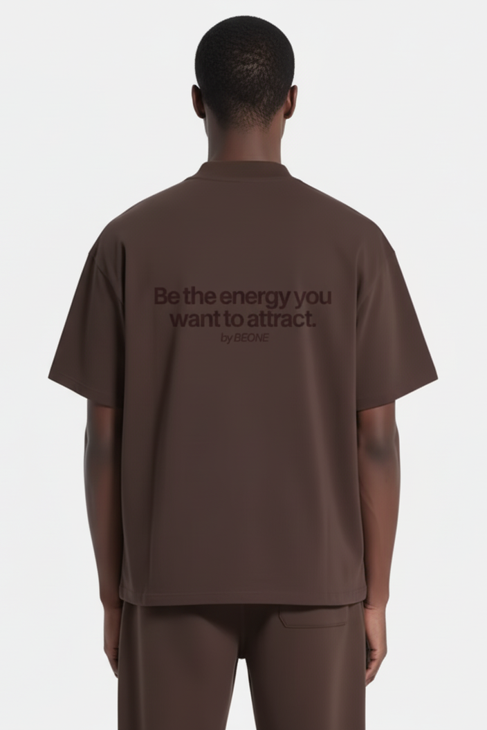 Person wearing a brown t-shirt with a motivational quote on the back against a white background