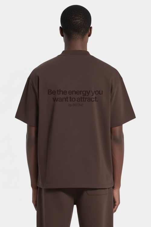 Person wearing a brown t-shirt with a motivational quote on the back against a white background