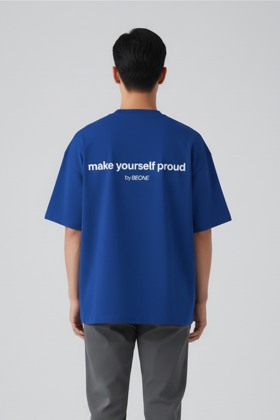 Person wearing a blue t-shirt with text on the back, standing against a plain background