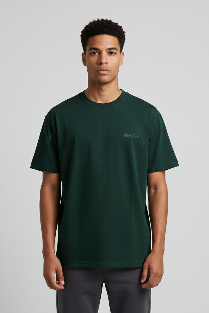 Person wearing a green t-shirt with a brand logo on a gray background