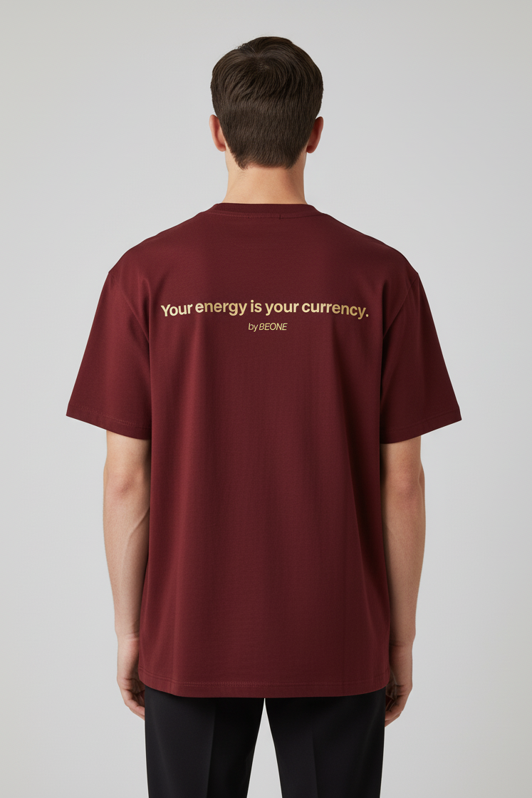 Man wearing a maroon t-shirt with text on the back against a gray background