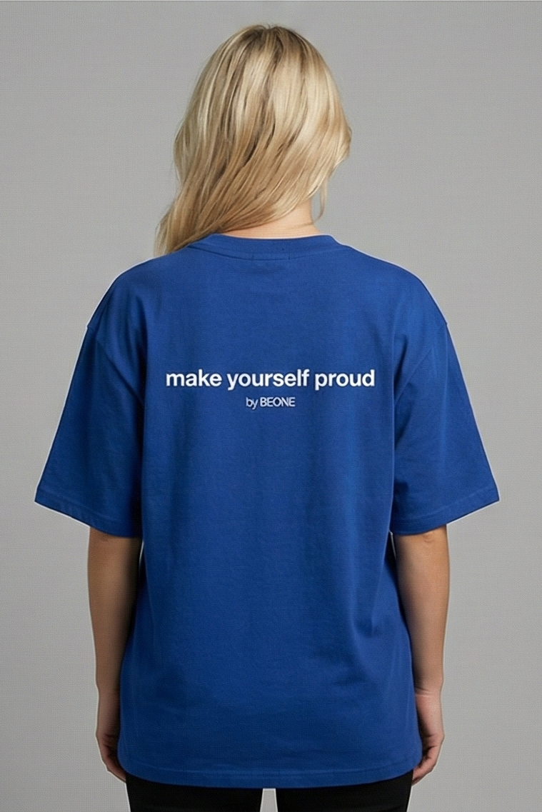 Person wearing a blue t-shirt with 'make yourself proud' text on the back against a gray background